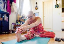 Een vrouw met een kaal hoofd als gevolg van behandeling tegen kanker doet yoga.